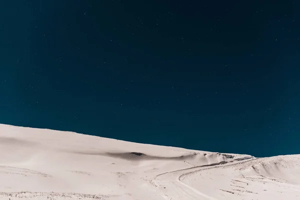 scenic view of mountain covered with pure snow against dark blue sky