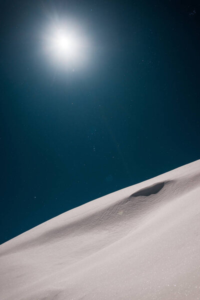 scenic view of mountain covered with snow and shining sun in dark sky