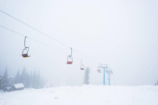 scenic view of snowy mountain with gondola lift in fog