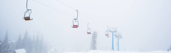 scenic view of snowy mountain with gondola lift in fog, panoramic shot