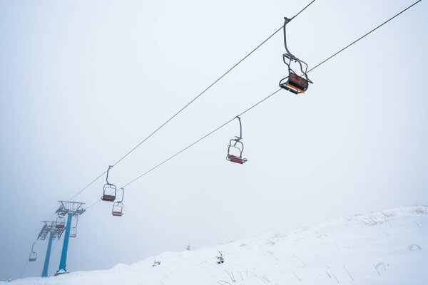 scenic view of snowy mountain with gondola lift in fog