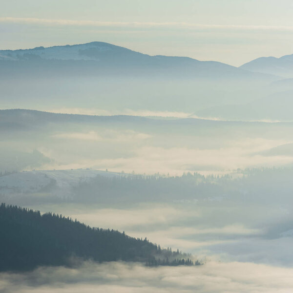 scenic view of snowy mountains with pine trees in white fluffy clouds