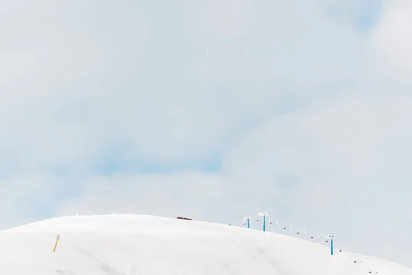 scenic view of snowy mountain with gondola lift and white fluffy clouds in sky