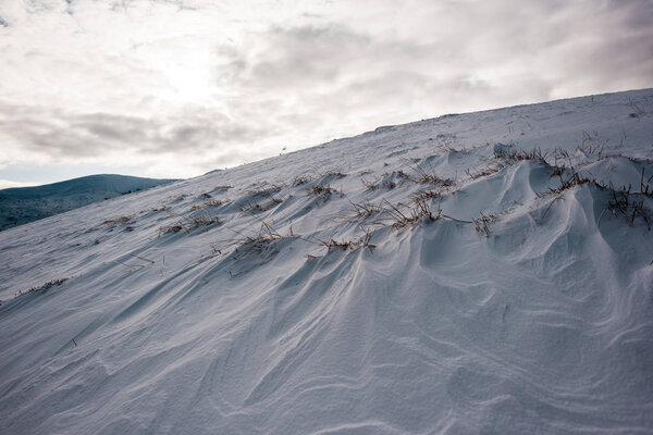 scenic view of snowy hill with cloudy sky on background