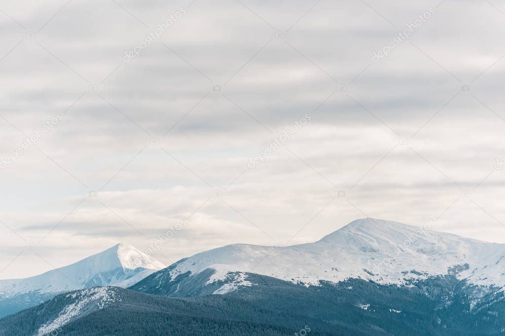 scenic view of snowy mountains in white fluffy clouds