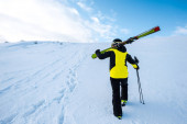 Rückansicht des Skifahrers beim Gehen mit Skistöcken auf Schnee 
