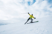 Aufgeregter Sportler hält Skistöcke in der Hand und fährt auf weißer Piste