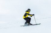 lyžař držící lyžařské hole a lyžování na sjezdovce v zimě 