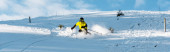panoramatický záběr lyžaře v helmě držícího lyžařské hole při lyžování na sjezdovce venku 