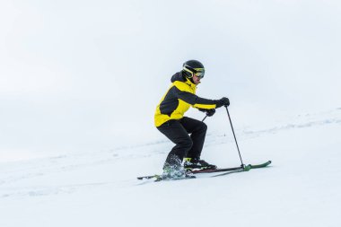 Kışın kayak sopası tutan ve yamaçta kayak yapan kayakçı. 