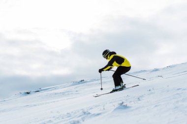 Kasklı ve gözlüklü sporcu kışın yamaçta kayak yapıyor. 
