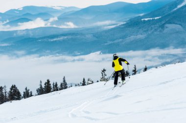 Dağların yamacında kask giyen sporcu kayak yapıyor. 