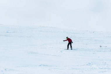 Dışarıda beyaz karla yamaçta gezen bir snowboardcu. 