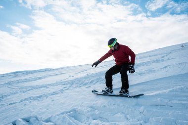 Atletik snowboardcu kışın mavi gökyüzüne karşı yamaçta 