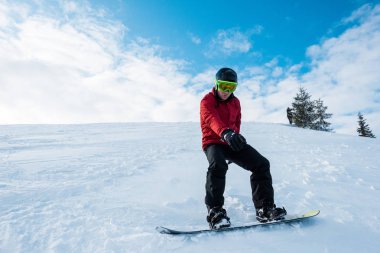 Atletik snowboardcu kışın bulutlu mavi gökyüzüne doğru gidiyor. 