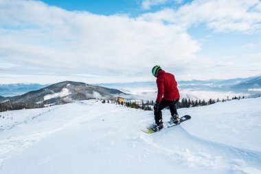Kışın yamaçta uçan kasklı snowboardcu. 