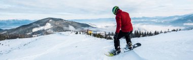 Kışın yamaçta kayak yapan snowboardcunun panoramik çekimi 