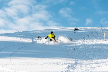 sportsman in helmet holding ski sticks while skiing on slope outside  clipart