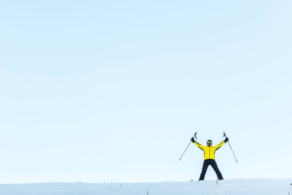 skier in helmet holding sticks while standing on snow 