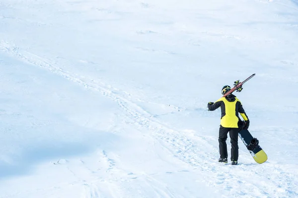 Kasklı Kayakçının Arka Manzarası Dağlarda Beyaz Kar Üzerinde Çubuklarla Yürümesi — Stok fotoğraf