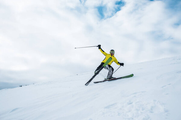 excited sportsman holding ski sticks and skiing on white slope