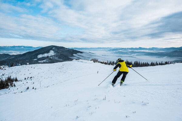 back view of skier in helmet skiing in wintertime 