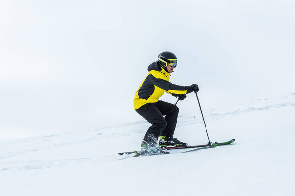 skier holding ski sticks and skiing on slope in wintertime 