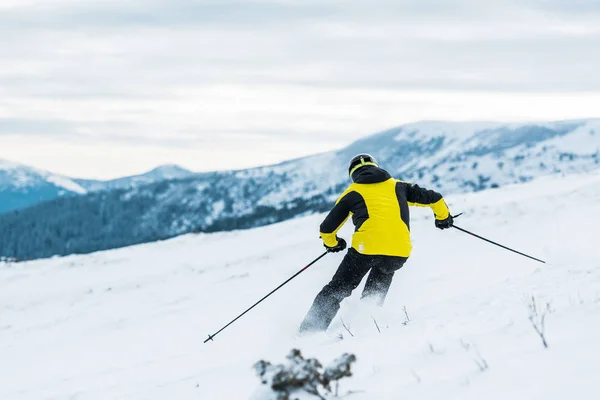 Achteraanzicht Van Skiër Helm Holding Sticks Skiën Piste Winter — Stockfoto