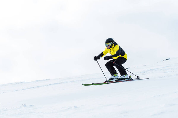 sportsman in helmet and goggles skiing on slope in winter 