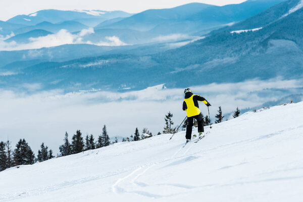 спортсмен в шлеме катается на лыжах на склоне возле гор
 