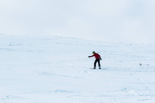 snowboarder riding on slope with white snow outside 