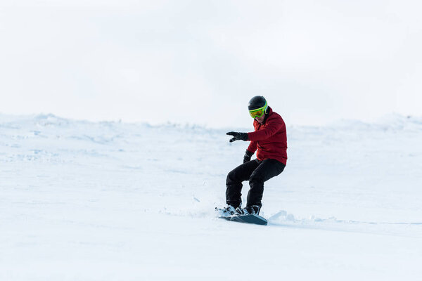 athletic snowboarder in helmet riding on slope outside 