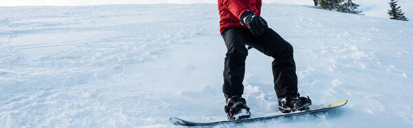 panoramic shot of snowboarder riding on slope in winter 