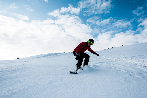 sportive snowboarder riding on slope with white snow in wintertime 