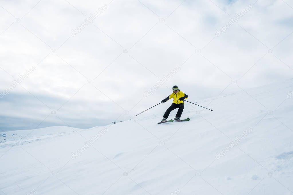 sportsman holding ski sticks and skiing on white slope 