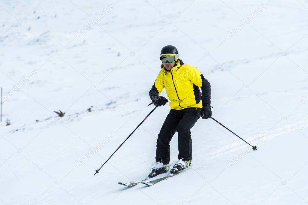 skier holding sticks and skiing on slope with snow 
