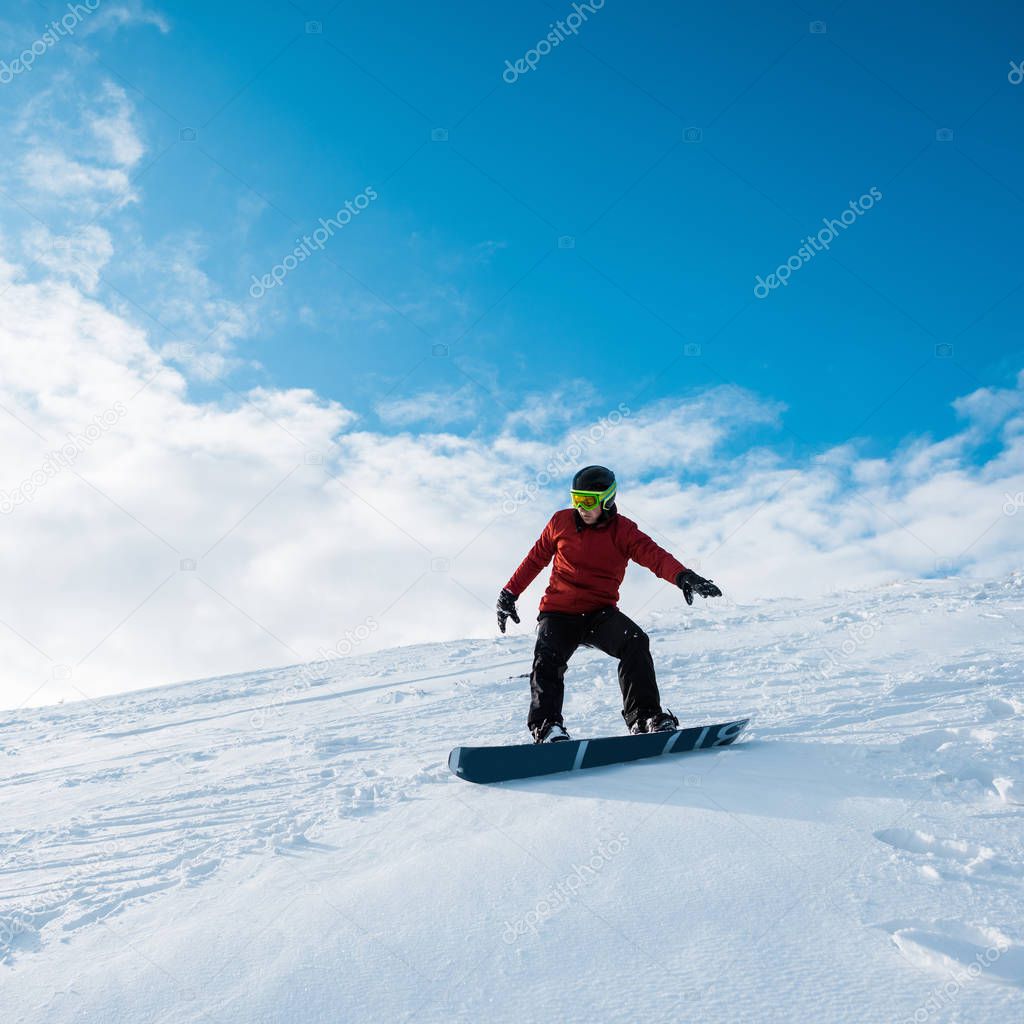 snowboarder in helmet riding on slope against blue sky 