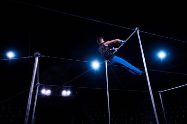 low angle view of gymnast performing on horizontal bars in arena of circus   clipart