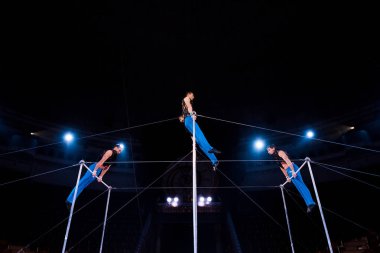 low angle view of gymnasts performing on horizontal bars in circus   clipart