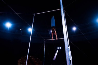 Sirk arenasındaki yatay barlarda akrobatın sahne arkası görüntüsü  