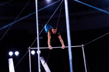 Sirk arenasındaki yatay barlarda gösteri yapan atletik jimnastikçilerin seçici odağı  