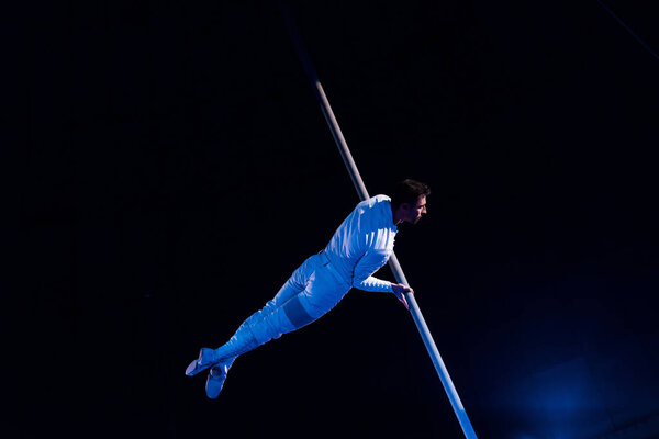 handsome acrobat balancing in arena of circus 