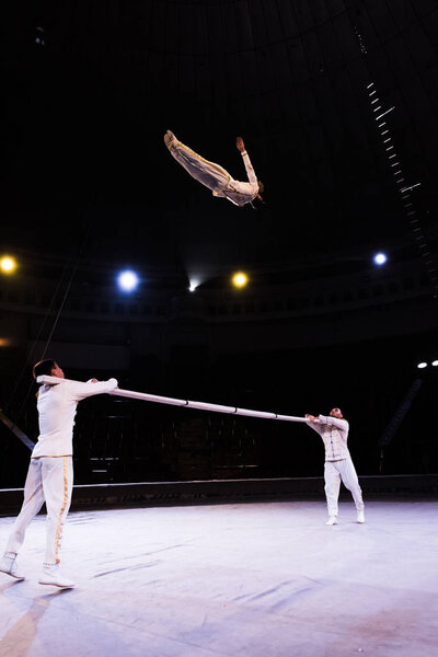 air acrobat jumping while performing near pole in circus 