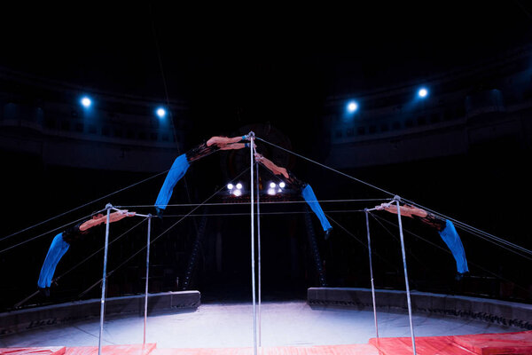four gymnasts performing on horizontal bars in circus  
