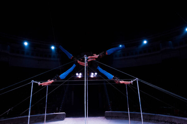 four gymnasts exercising on horizontal bars in circus  