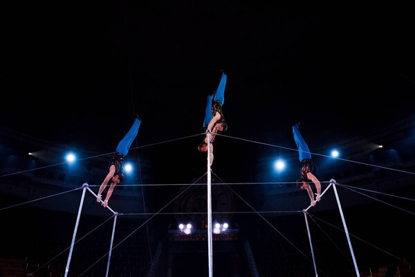 low angle view of gymnasts performing on horizontal bars in circus  