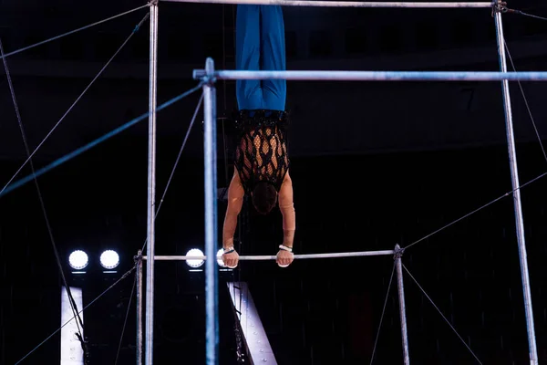 Back view of athletic gymnast performing on horizontal bars in arena of circus — Stock Image Back View Athletic Gymnast Performing Horizontal Bars Arena Circus Stock Photo