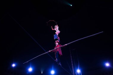 low angle view of man holding pole and supporting attractive acrobat while walking on rope  clipart