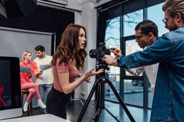 Yakışıklı sanat yönetmeninin seçici odağı fotoğrafçı ve asistanın yanında duruyor. 