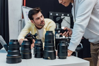Fotoğrafçı ve kamera lenslerinin yanında duran sanat yönetmeninin kırpılmış görüntüsü 